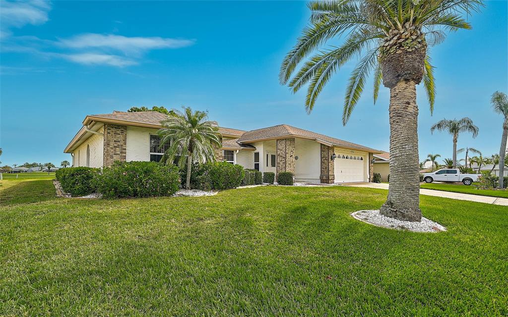 A single-story house with a beige exterior, brick accents, and a palm tree in the yard — 4360 PRESIDENTIAL AVENUE CIRCLE E, BRADENTON, FL
