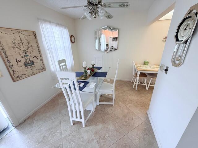 A dining room features a glass table, white chairs, tile flooring, and a ceiling fan — 174 Prescott I, Deerfield Beach FL 33442, DEERFIELD BEACH, FL