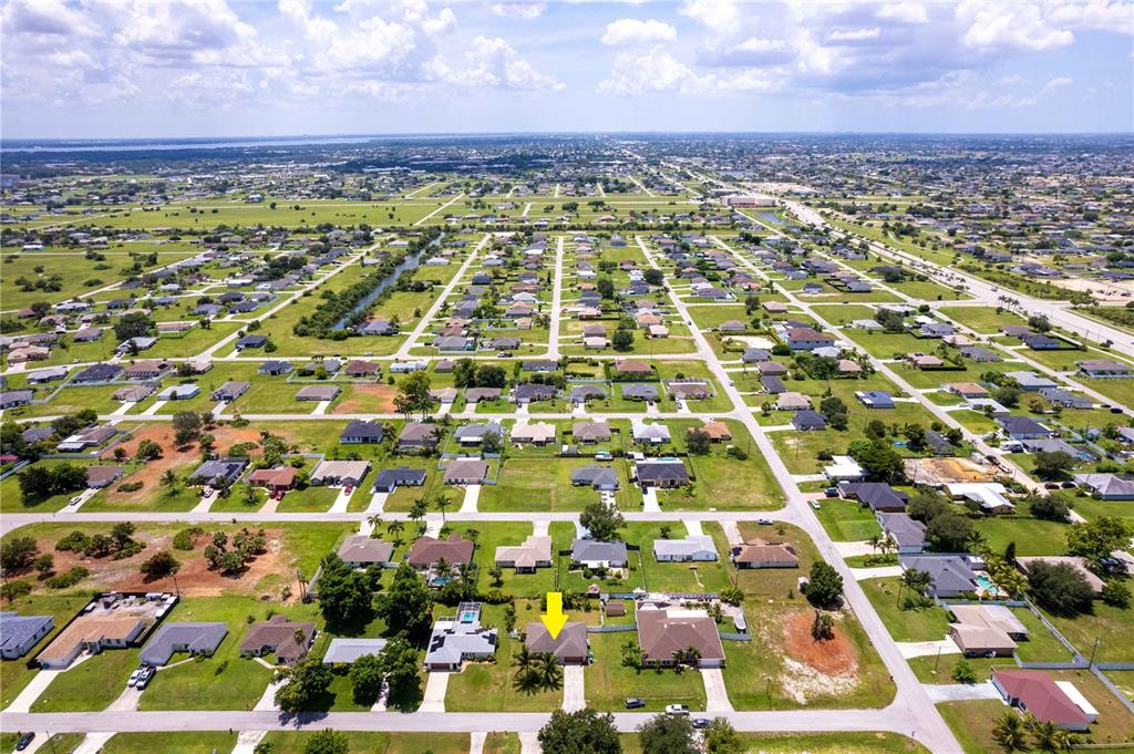 An aerial view shows a residential neighborhood with a yellow arrow pointing to a house — 1728 NE 22ND TERRACE, CAPE CORAL, FL