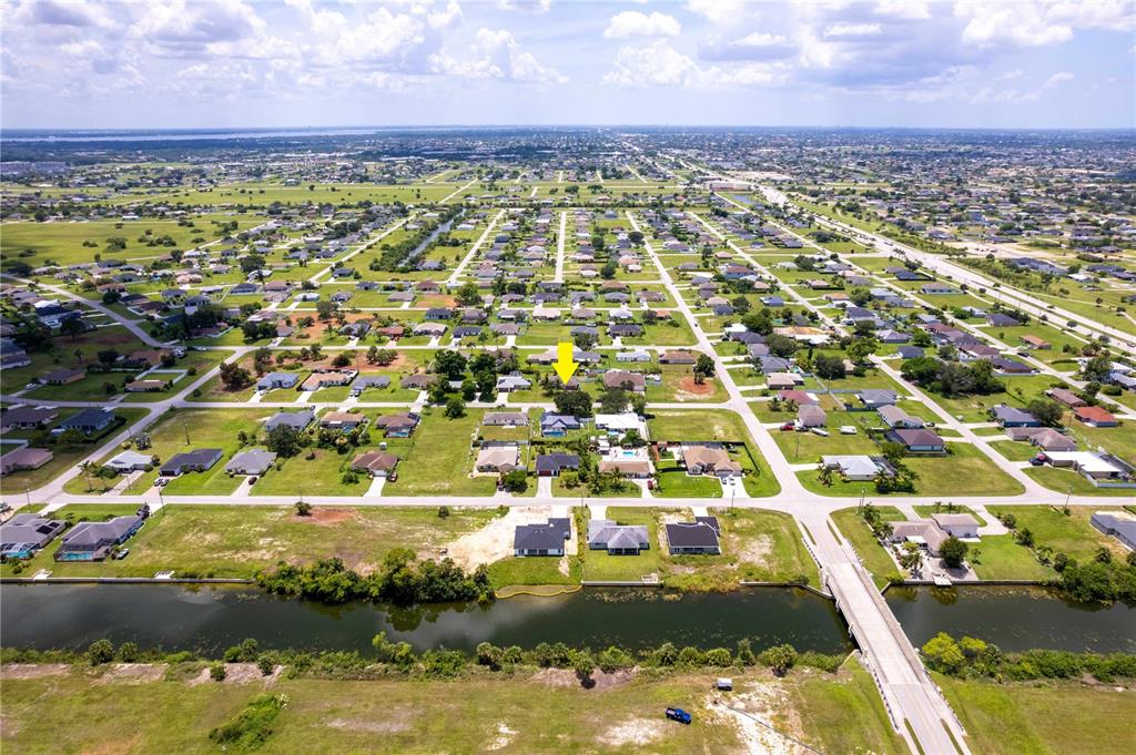 An aerial view shows a residential neighborhood with a canal and a bridge — 1728 NE 22ND TERRACE, CAPE CORAL, FL