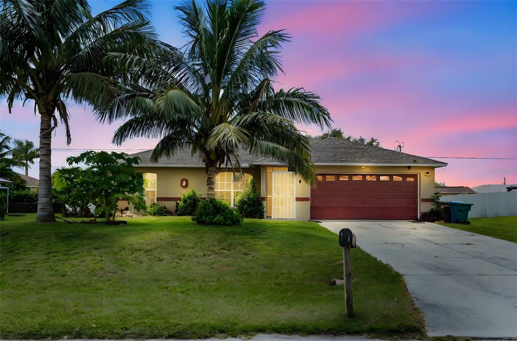 A single-story house with a red garage door, palm trees, and a concrete driveway — 1728 NE 22ND TERRACE, CAPE CORAL, FL