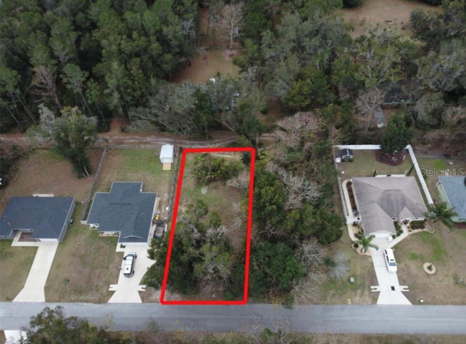 An aerial view shows a vacant, rectangular residential lot outlined in red between two houses — 0 NW 45 STREET, OCALA, FL