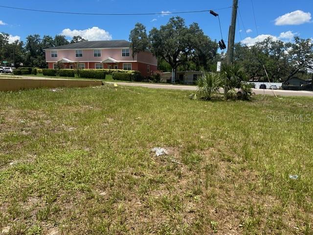 A grassy vacant lot sits in front of a two-story pink residential building — 1904-1906 W BUSCH BOULEVARD, TAMPA, FL