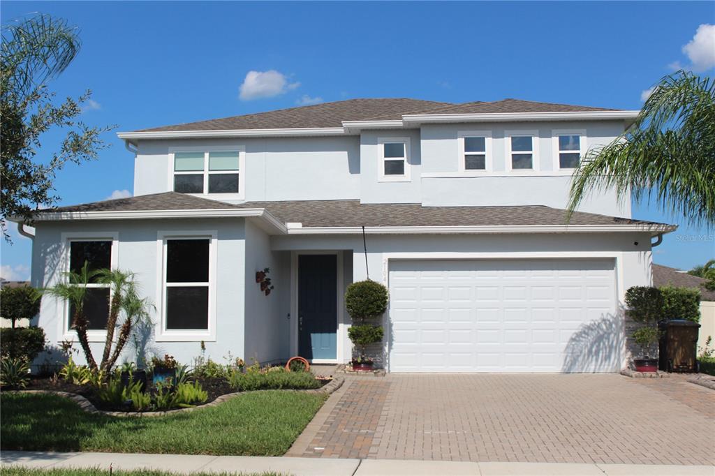 A two-story house with a light blue exterior, a two-car garage, and a paved driveway — 2104 STILLWOOD WAY, ST CLOUD, FL