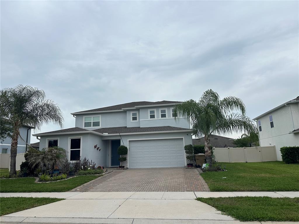 A two-story house with a light blue exterior, a two-car garage, and a paved driveway — 2104 STILLWOOD WAY, ST CLOUD, FL