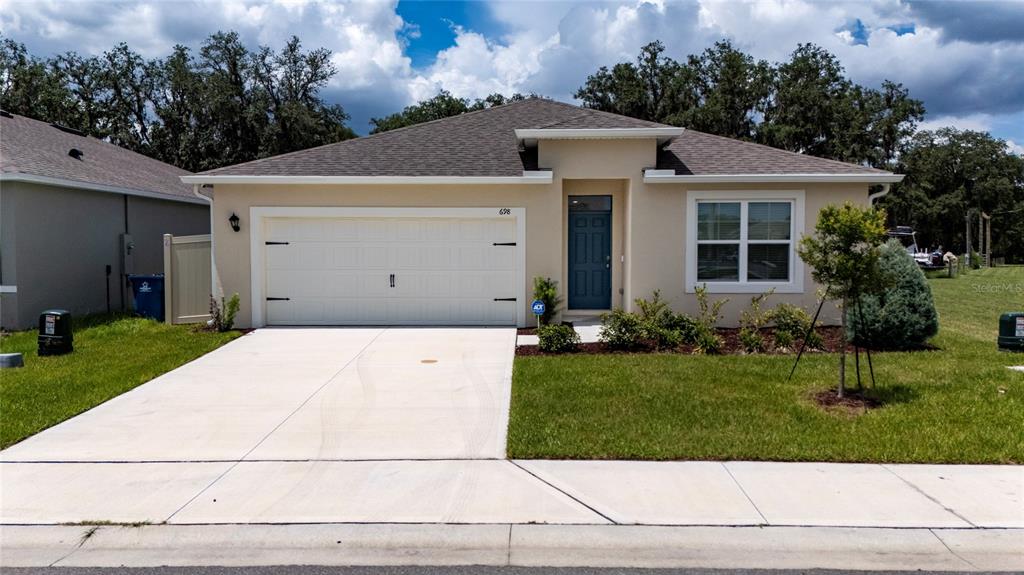 A single-story suburban house features a two-car garage, a blue front door, and a lawn — 698 PARK PLACE BOULEVARD, DAVENPORT, FL