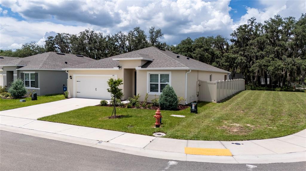 A single-story house with a white garage door, beige siding, and a concrete driveway — 698 PARK PLACE BOULEVARD, DAVENPORT, FL