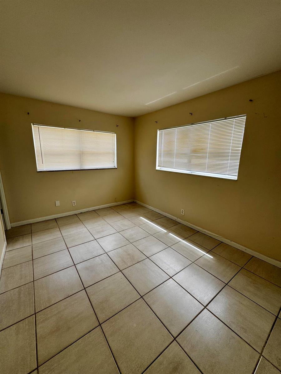 An empty room with beige walls, tile flooring, and two windows with closed blinds — 2824 N Dixie Highway, Boca Raton FL 33431, BOCA RATON, FL