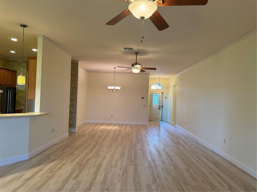 An open-concept living area features light wood-look flooring, two ceiling fans, and a dining chandelier — 2470 SALZBURG LOOP, WINTER HAVEN, FL