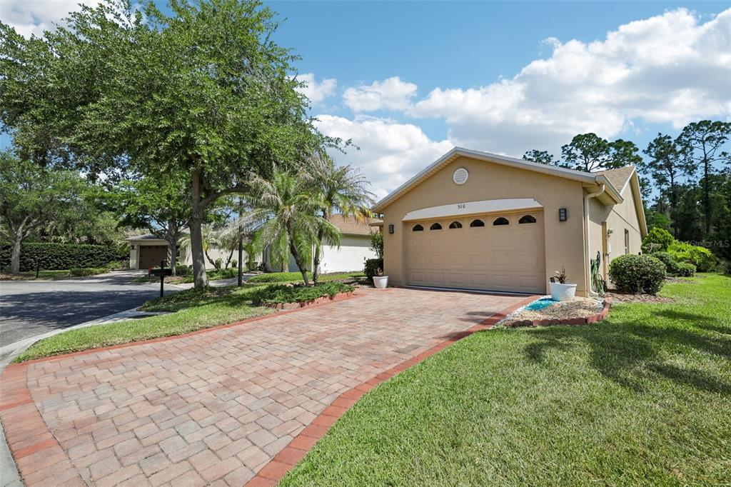 A tan single-story house with a brick paver driveway and a two-car garage — 516 MILLIFIORA LANE, POINCIANA, FL