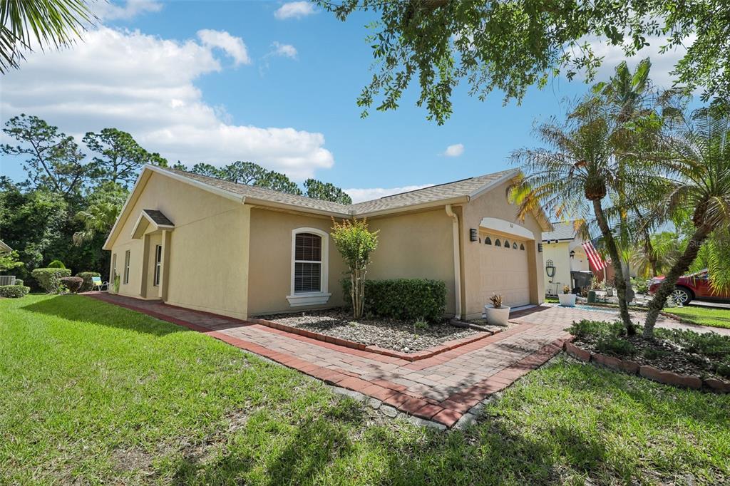 A tan, single-story house with a paved walkway, a two-car garage, and a manicured lawn — 516 MILLIFIORA LANE, POINCIANA, FL