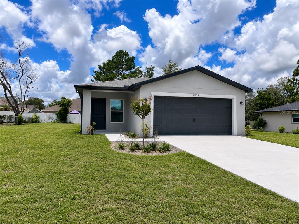 A single-story house with a gray exterior, dark garage door, and a concrete driveway — 11199 MURRAYSVILLE DRIVE, SPRING HILL, FL