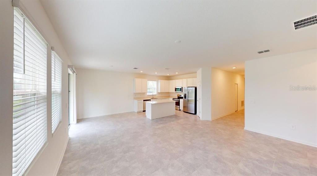 An open-concept kitchen and living area features white cabinetry, a center island, and tile flooring — 203 BRAVE ROAD, DAVENPORT, FL