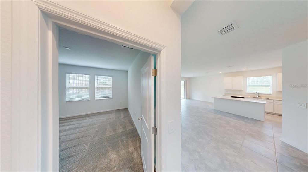 A view from a doorway looking into a carpeted bedroom and an adjacent tiled kitchen — 203 BRAVE ROAD, DAVENPORT, FL