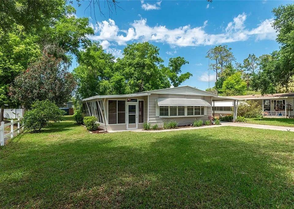 A light-colored single-story house with a screened-in porch and a large grassy yard — 2420 SE 175TH TERRACE, SILVER SPRINGS, FL