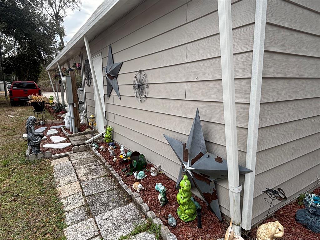 The exterior of a house features beige horizontal siding, metal star decorations, and garden ornaments — 2420 SE 175TH TERRACE, SILVER SPRINGS, FL