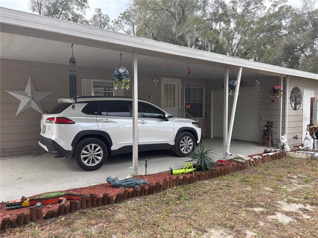 A white SUV is parked under the covered carport of a single-story house — 2420 SE 175TH TERRACE, SILVER SPRINGS, FL