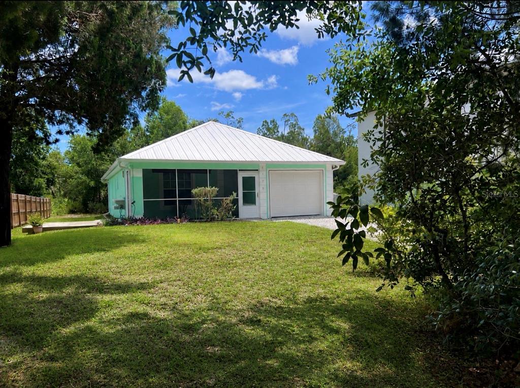 A light green house with a white metal roof, screened porch, and attached garage — 8170 130TH STREET, SEBASTIAN, FL