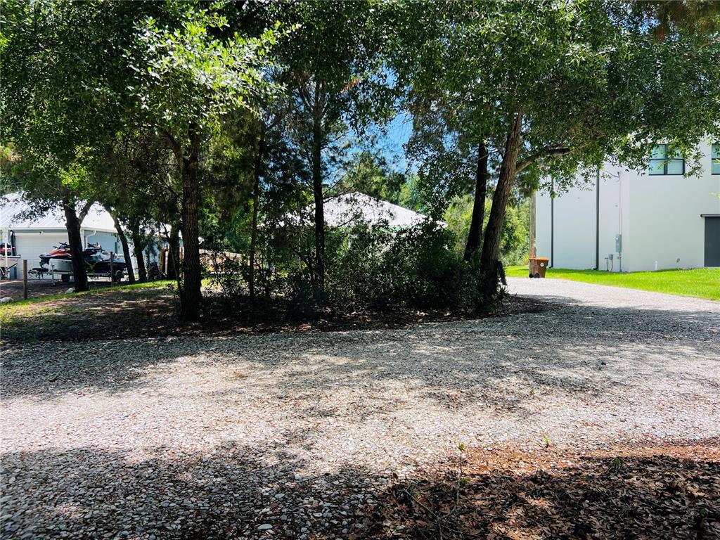 A gravel driveway leads toward trees and a white building under a blue sky — 8170 130TH STREET, SEBASTIAN, FL