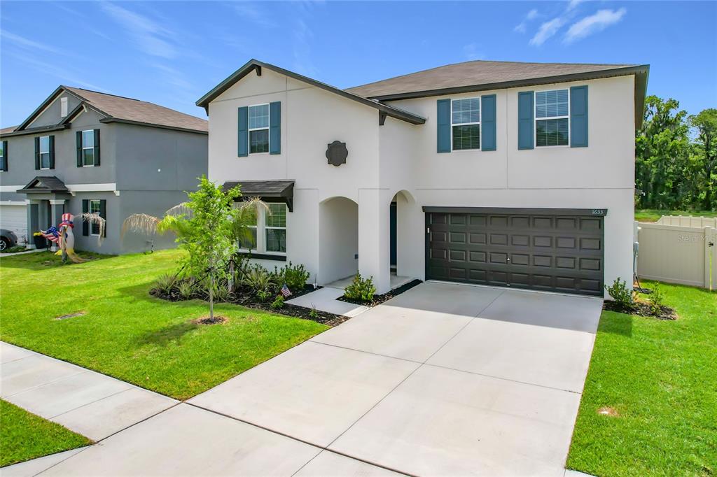 A two-story house with a white stucco exterior, dark shutters, and a two-car garage — 1633 RED LOOP, LAKELAND, FL