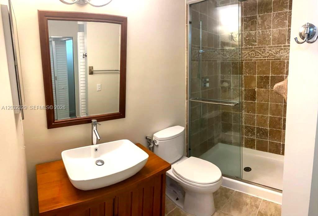 A bathroom features a vessel sink on a wooden vanity, a toilet, and a shower — 125 S Laurel Dr # 506, Margate FL 33063, MARGATE, FL