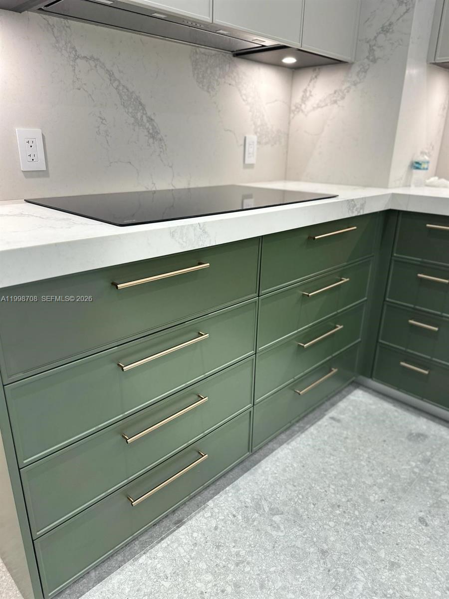 A kitchen features green cabinets with gold hardware and a white marble-patterned countertop — KEY BISCAYNE, FL