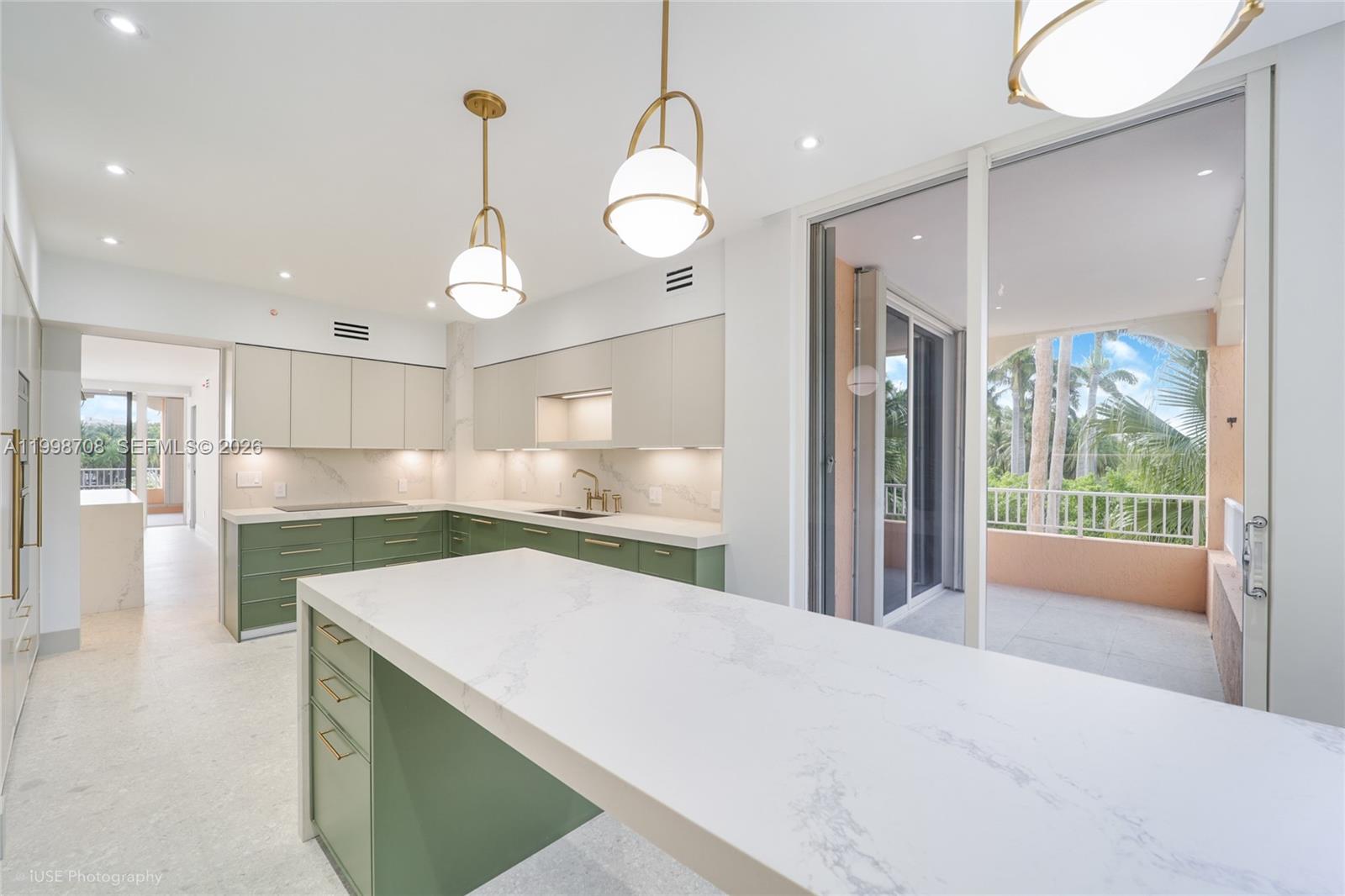 A modern kitchen features green lower cabinets, white upper cabinets, marble countertops, and a balcony — KEY BISCAYNE, FL