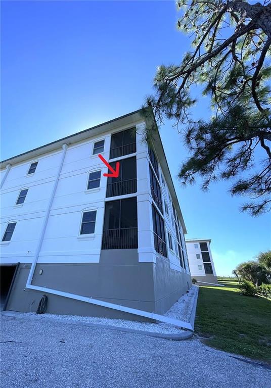 A low-angle exterior view of a multi-story apartment building with screened-in balconies — 9203 GRIGGS ROAD UNIT 204, ENGLEWOOD, FL