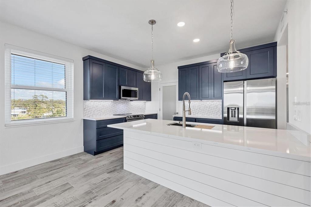 A modern kitchen features navy blue cabinets, white quartz countertops, and a shiplap kitchen island — 9203 GRIGGS ROAD UNIT 204, ENGLEWOOD, FL