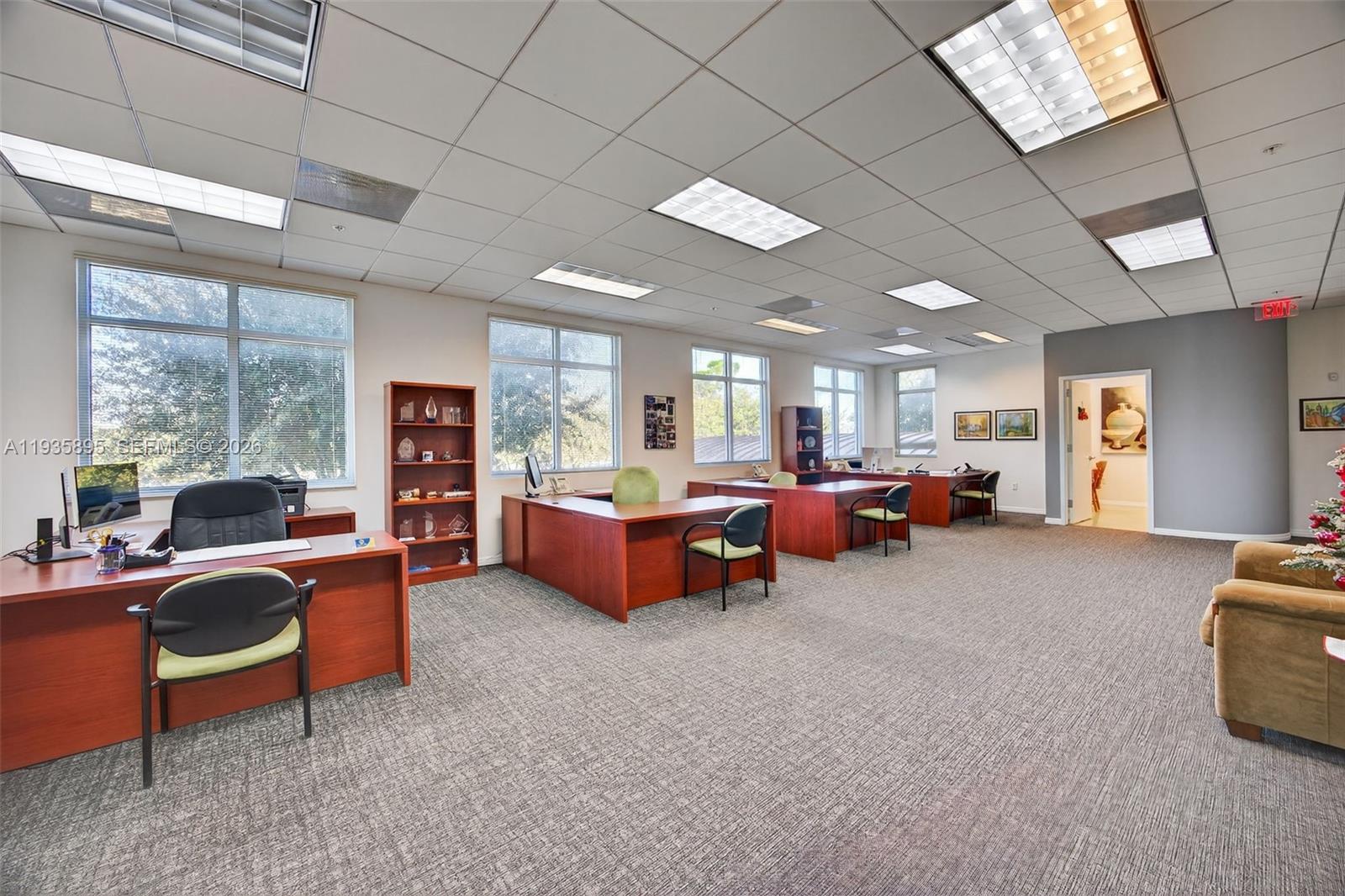 An office space features multiple wooden desks, rolling chairs, and large windows under a drop ceiling — 8501 SW 124th Ave # 201, Miami FL 33183, MIAMI, FL