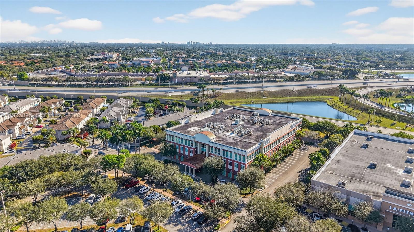 An aerial view shows a multi-story office building surrounded by parking lots and a pond — 8501 SW 124th Ave # 201, Miami FL 33183, MIAMI, FL