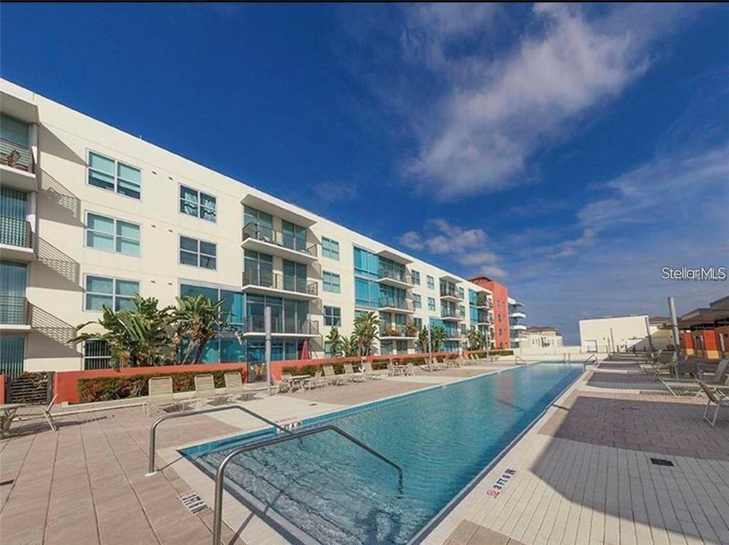 A long rectangular swimming pool sits beside a multi-story apartment building with balconies — 1208 E KENNEDY BOULEVARD UNIT 825E, TAMPA, FL