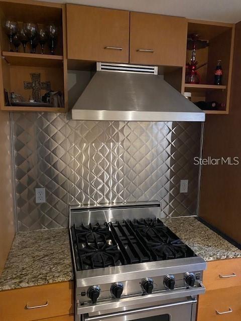 A kitchen features a stainless steel range hood, a gas stove, and a diamond-patterned backsplash — 1208 E KENNEDY BOULEVARD UNIT 825E, TAMPA, FL