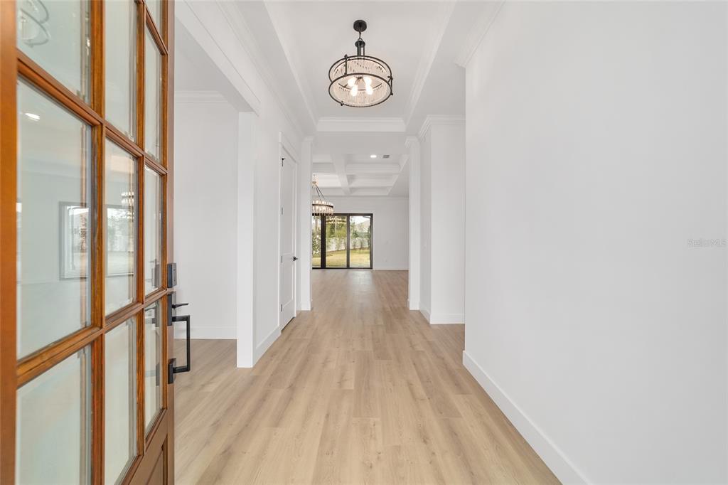 A bright entryway leads into a living area with light wood floors and tray ceilings — 5775 SW 43RD PLACE, OCALA, FL