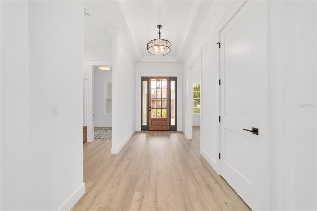 A bright entryway features light wood flooring, white walls, a tray ceiling, and a wooden door — 5775 SW 43RD PLACE, OCALA, FL