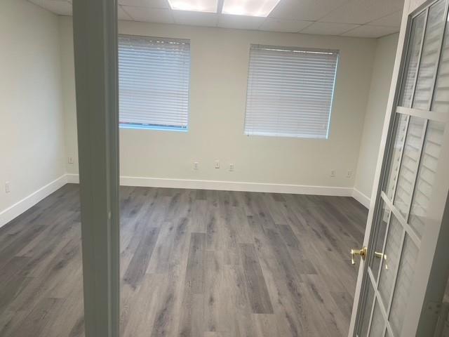 An empty office room features light gray wood-look flooring, white walls, and two windows — 5220 University Drive # 109c, Davie FL 33328, DAVIE, FL