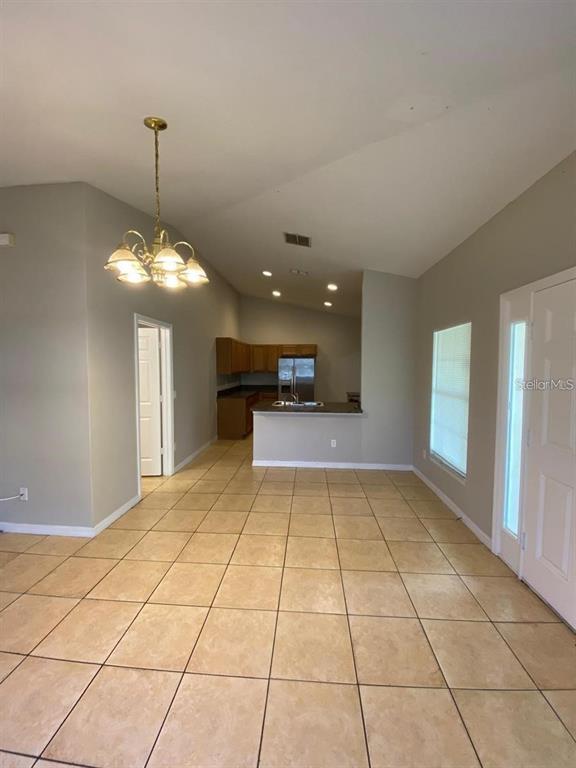 A tiled dining area features a chandelier and an open view into the kitchen — 502 BLACKBIRD LANE UNIT A, POINCIANA, FL