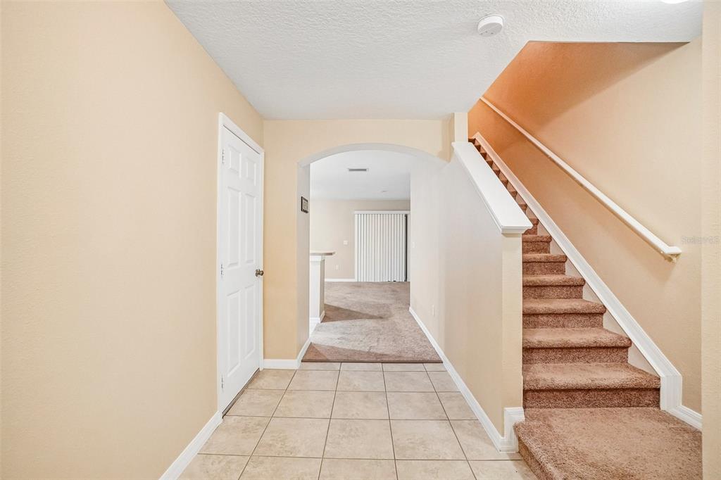 An entryway with tile flooring, a carpeted staircase, and an arched doorway leading to a room — 2516 OLEANDER LAKES DRIVE, BRANDON, FL