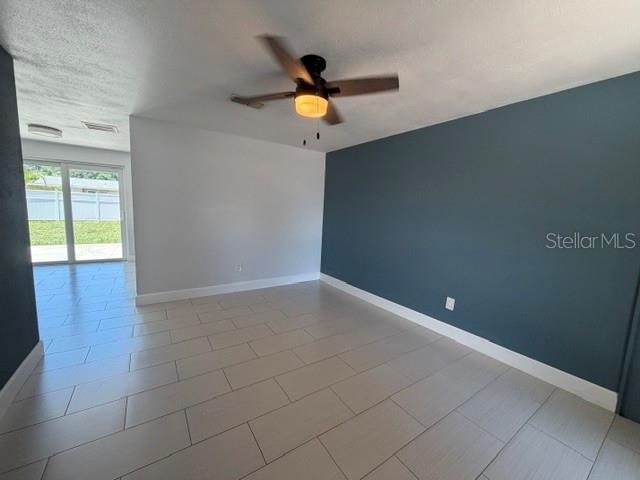 A room with light-colored tile flooring, a ceiling fan, and a dark blue accent wall — 7904 WOODVINE CIRCLE, TAMPA, FL