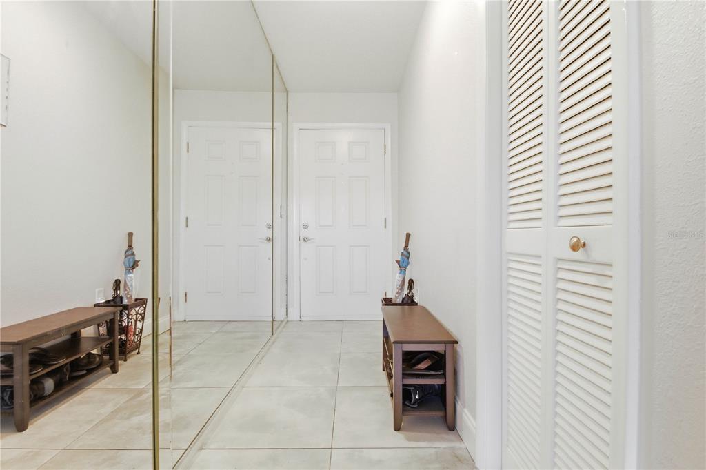 An entryway features tiled floors, a mirrored wall, a wooden shoe bench, and louvered closet doors — 260 MICHAELS CIRCLE, OLDSMAR, FL
