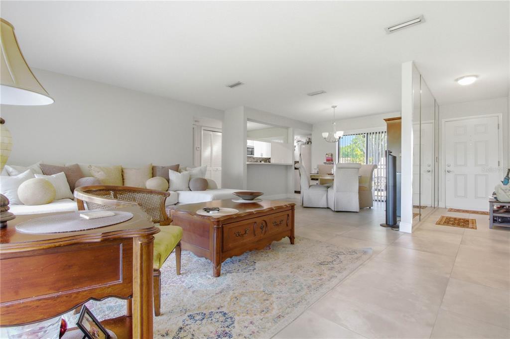 A living room with tile floors, a wooden coffee table, and an adjacent dining area — 260 MICHAELS CIRCLE, OLDSMAR, FL