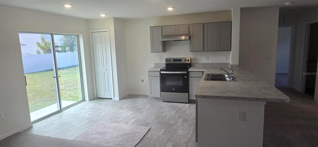 A kitchen with gray cabinets, stainless steel appliances, and a sliding door to the backyard — 410 DANUBE DRIVE, POINCIANA, FL