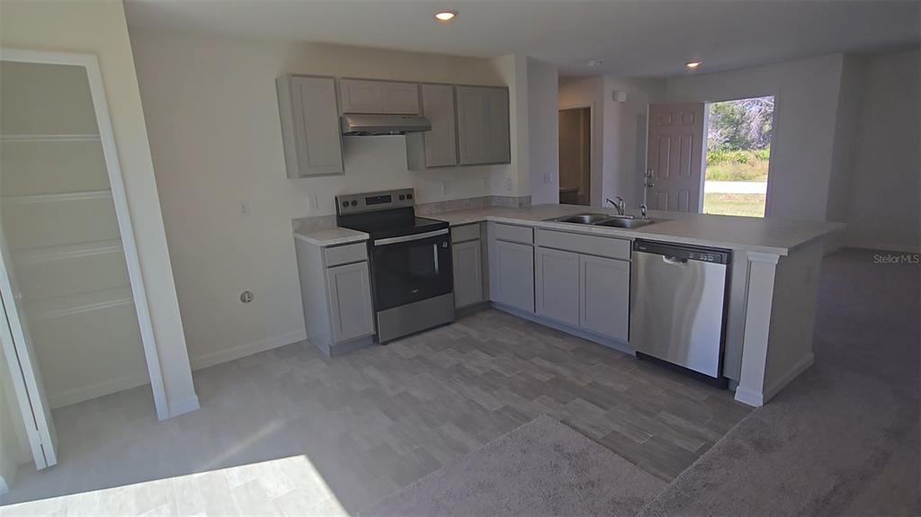 A kitchen features gray cabinets, stainless steel appliances, and light-colored tile flooring — 410 DANUBE DRIVE, POINCIANA, FL
