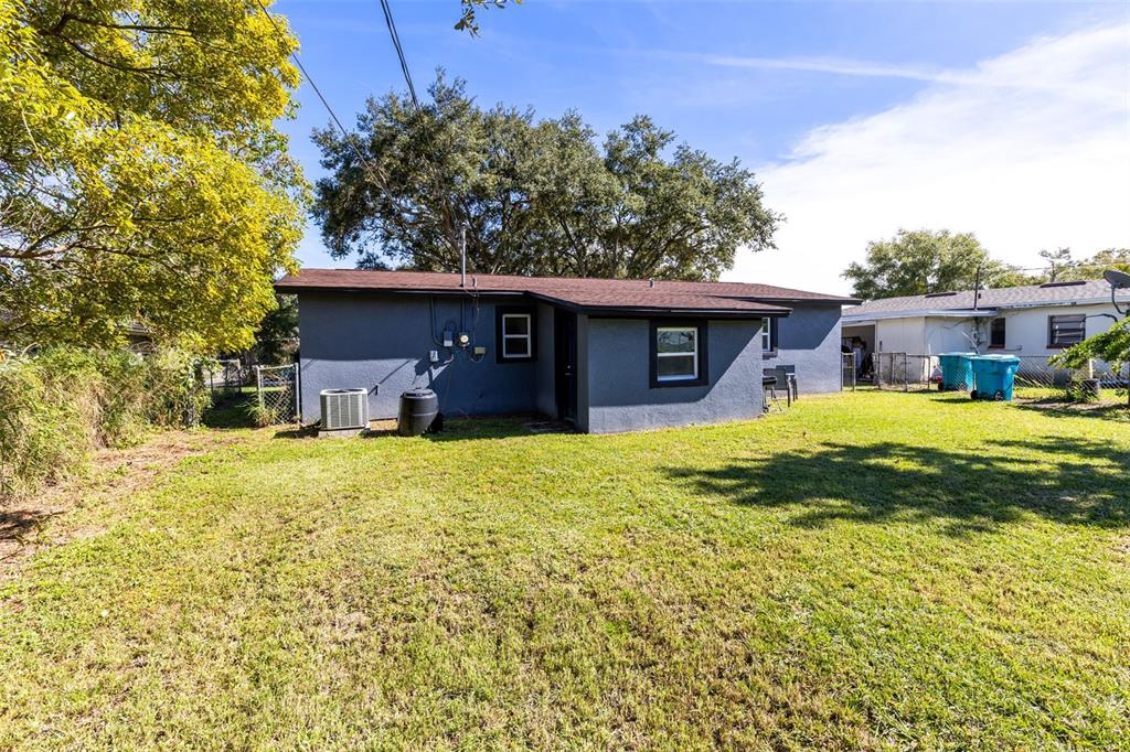The exterior of a gray, single-story house features a lawn, trees, and a central window — 2190 PATTERSON AVENUE, ORLANDO, FL