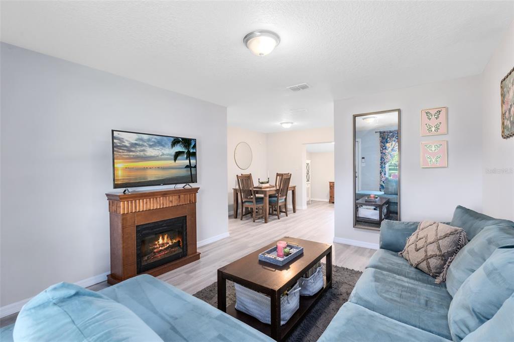 A living room features a fireplace with a television, a blue sofa, and a dining area — 2190 PATTERSON AVENUE, ORLANDO, FL