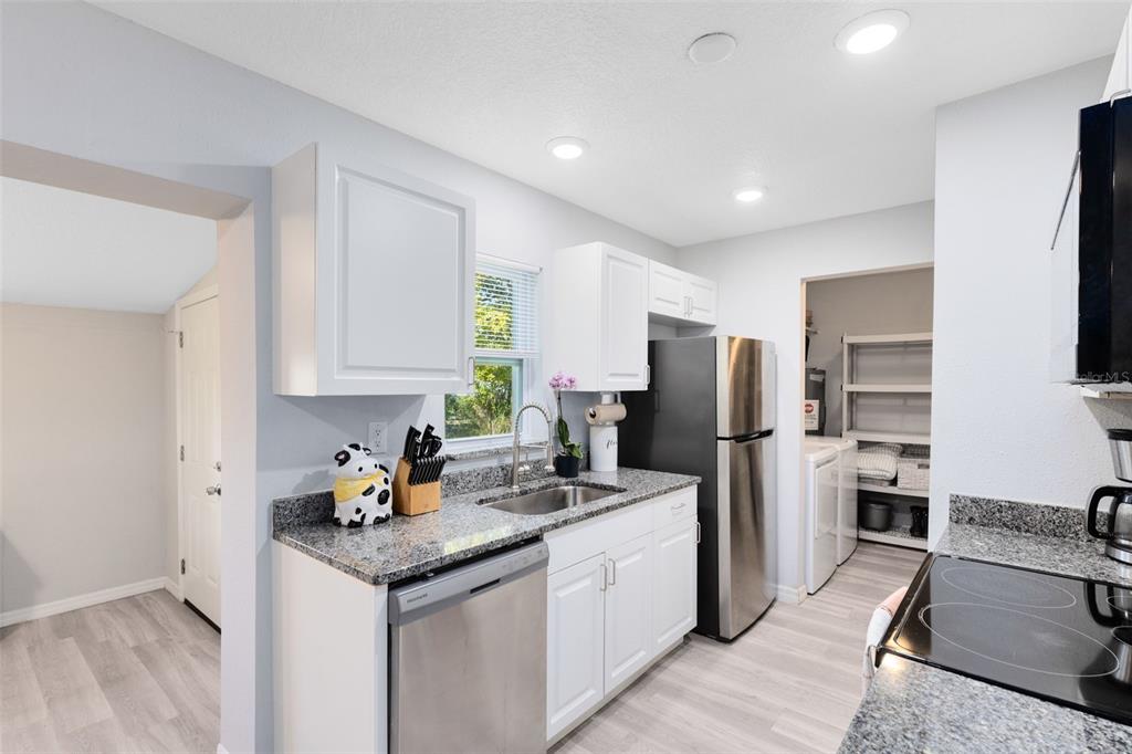 A kitchen features white cabinets, granite countertops, stainless steel appliances, and light wood-look flooring — 2190 PATTERSON AVENUE, ORLANDO, FL