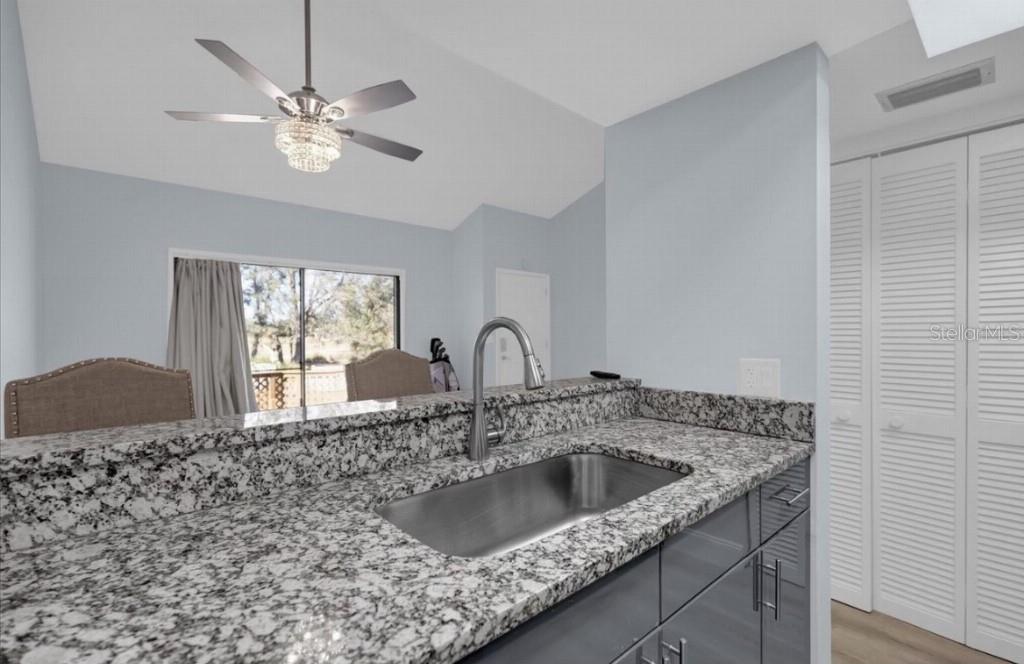 A kitchen sink with a granite countertop and gray cabinets overlooks a dining area — 321 BOBBY JONES ROAD UNIT 321, SARASOTA, FL