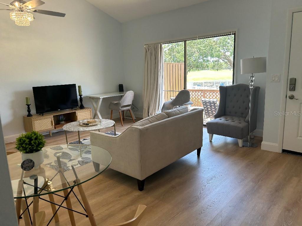 A living room features a sofa, television, desk, and sliding glass doors leading to a balcony — 321 BOBBY JONES ROAD UNIT 321, SARASOTA, FL