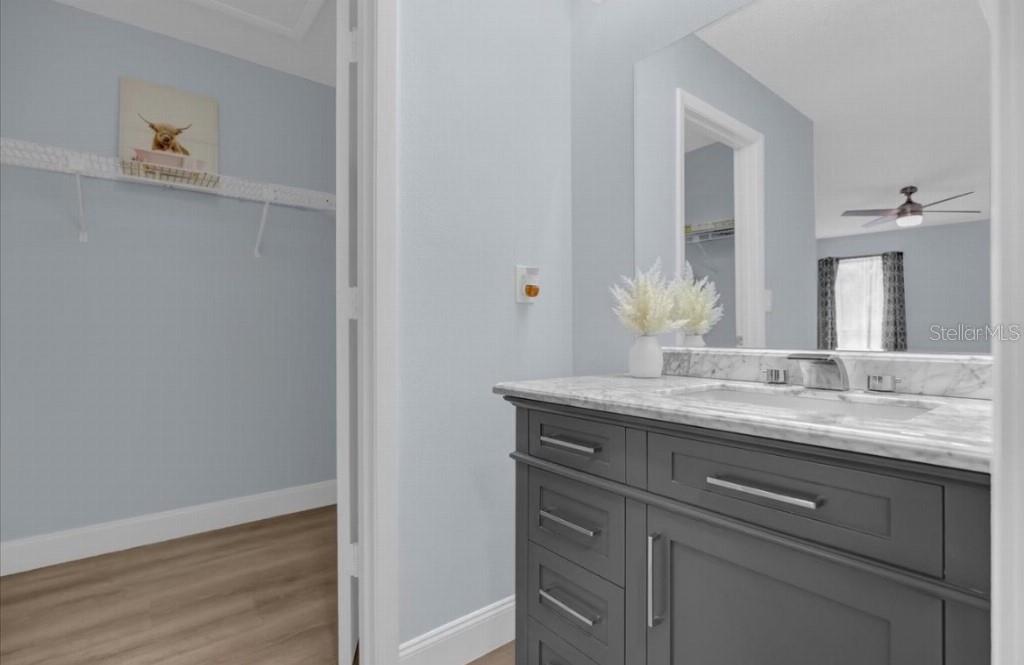 A bathroom vanity with a marble countertop sits next to an open walk-in closet — 321 BOBBY JONES ROAD UNIT 321, SARASOTA, FL