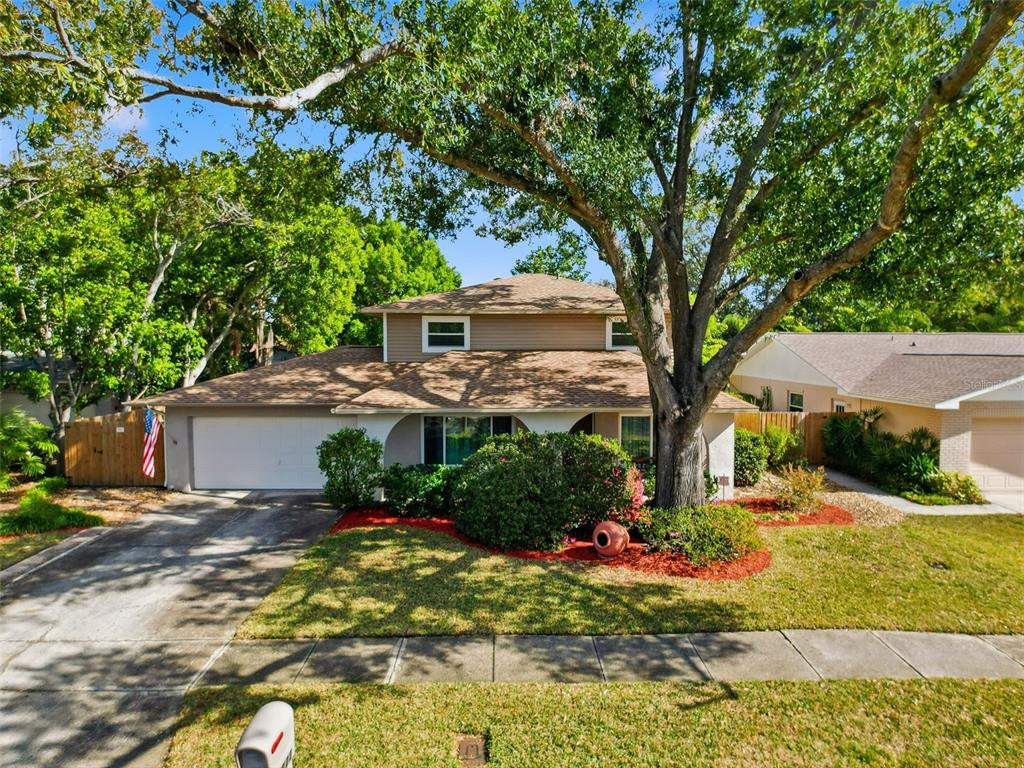 A two-story house with a tan exterior, a two-car garage, and a large front tree — 7923 SINGING COURT PLACE, TAMPA, FL